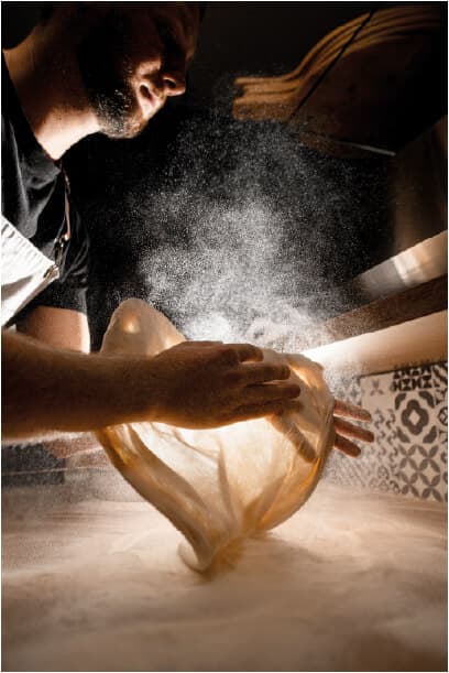 Artigiana sorridente mostra un manufatto in ceramica davanti al suo laboratorio